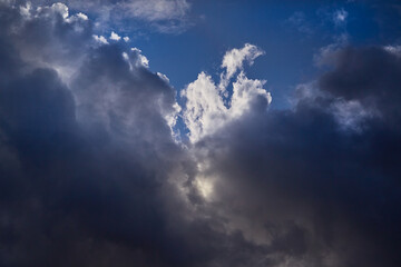 The bright sun illuminates the tops of dark clouds, leaving the lower layers in shadow. Deep contrast creates a striking natural balance of light and darkness.