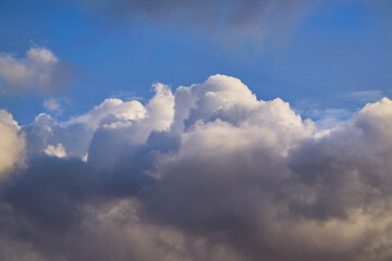 A celestial landscape with voluminous clouds and bright sun flares. Dense clouds are wrapped in a play of light and shadow, creating a sense of airy lightness.