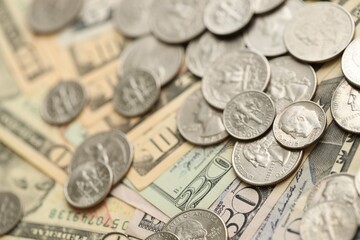 Many different dollar bills and silver cent coins under natural light