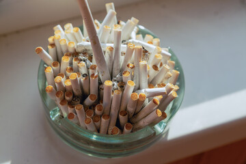 The consequences of smoking in everyday life. A polluted ashtray with cigarette butts on a...