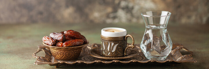 Cup of coffee and glass of water and dry dates on saucer ready to eat for iftar time. Islamic...