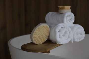 relaxation, spa, treatments. on the edge of the bath there are folded white towels, a brush and a washcloth