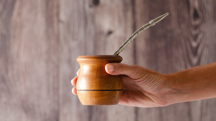 A female hand holding a wooden mate on wooden background. 