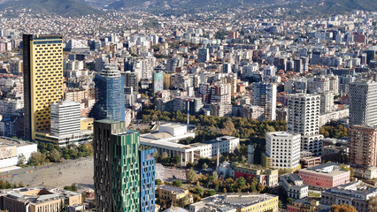Aerial view of Tirana’s city center on a sunny day, showcasing Skanderbeg Square, modern high-rises, and historic landmarks, with Dajti Mountain in the background. Photo taken 16,11,2024, Tirana, Alba