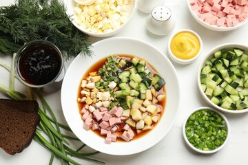 Tasty okroshka soup with kvass and ingredients on white marble table, flat lay