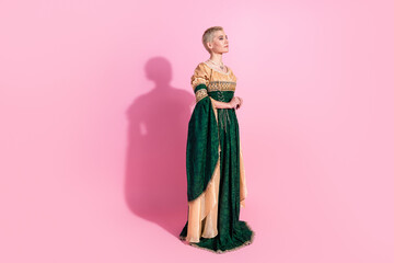 Fototapeta premium Young woman in medieval attire against a pink background showcasing elegance