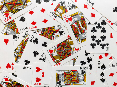 This image captures a visually striking arrangement of playing cards scattered across a surface. The mix of suits hearts, diamonds, clubs, and spades creates an engaging flatlay pattern 