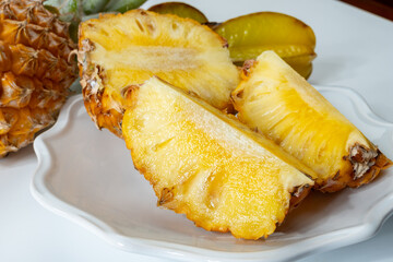 Two whole fresh ripe pineapples or sweet baby ananas and starfruits on white background close up