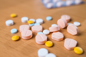 Assorted colorful medicine pills on wooden table