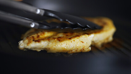 Pan-frying a piece of chicken fillet.