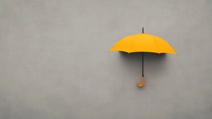 Yellow umbrella on grey background, protection concept