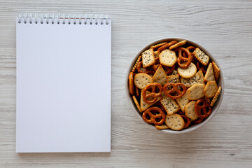Homemade Salty Party Snack Mix in a Bowl, blank notepad, top view.