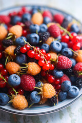 Mixed berries in a blue plate close up. Blueberries, raspberries, redcurrant, blackcurrant and...