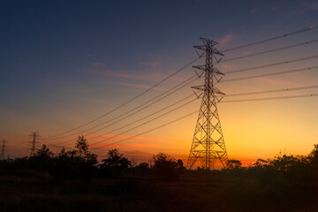 Silhouette of high voltage electric pole in early morning with clouds and sky in the background.
