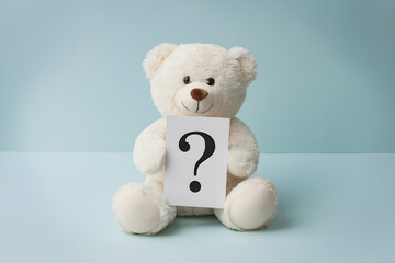 A teddy bear holding a card with a question mark