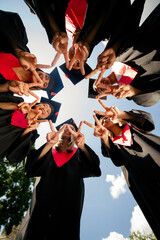 Low ange view vertical photo of groupmates students smile touch fingers mortarboard gown graduate...