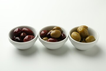 Tasty marinated olives in bowls on white table
