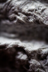 Extreme close up of old gray handmade paper clay with a structure and rough texture. Paper recycling. Selective soft focus, shallow depth of field.