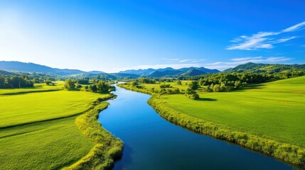 Obraz premium A stunning aerial view of a tranquil river meandering through lush green hills under a clear blue sky. The vibrant colors of nature create a serene and peaceful outdoor scene.