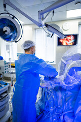 Surgeon in modern theater. A surgeon in blue scrubs works diligently at a surgical table with...