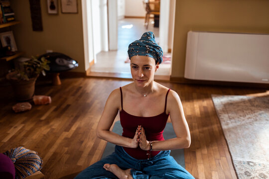 Woman meditating indoors with headscarf practicing yoga at home