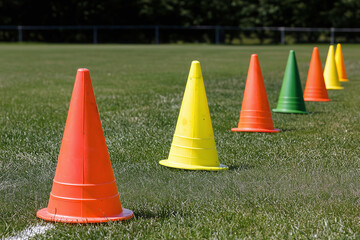 Vibrant agility cones arranged on grassy field, showcasing bright colors like orange, yellow, green, and red. Perfect for training and sports activities