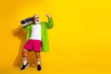 Eccentric elderly man in vibrant retro fashion with yellow background