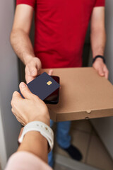 Woman using black credit card for payment of Pizza delivery man, close-up