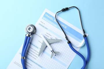 Medical tourism. Travel insurance application form, stethoscope and plane model on light blue...