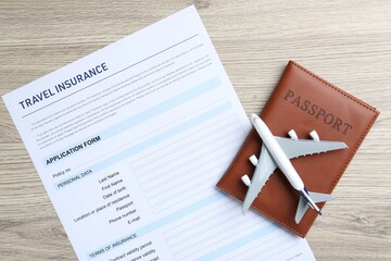 Medical tourism. Travel insurance application form, passport and airplane model on light wooden...