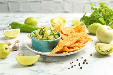 Delicious salsa with nachos on white marble table