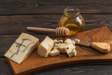 Hard goat cheese and a jar of organic honey. Cheese plate.
