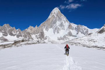A man is walking on a snowy mountain with a red backpack
