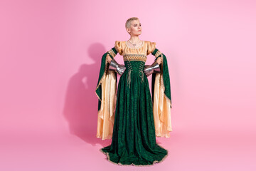 Fototapeta premium Young woman in medieval queen costume posing against a pink background