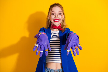 Charming woman in a blue jacket showcasing colorful jewelry with a cheerful smile on a vibrant yellow background