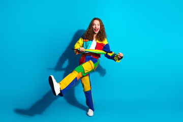 Obraz premium Smiling woman in colorful outfit joyfully posing on a vibrant blue background