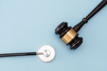 Justice Gavel and stethoscope on light blue background, Healthcare and medical law concept