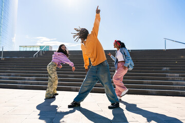 Multiethnic group of young hip hop dancers wearing colorful streetwear dancing outdoors - Stylish...