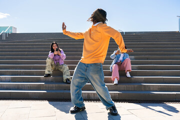 Multiethnic group of young hip hop dancers wearing colorful streetwear dancing outdoors - Stylish...