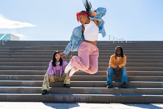 Multiethnic group of young hip hop dancers wearing colorful streetwear dancing outdoors - Stylish multiracial rap crew members meeting and having fun together