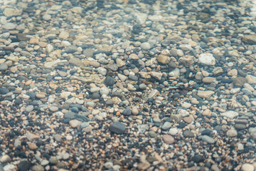 close-up of small pebbles at the beach, round pebbles, in the water of the lake in Savoie