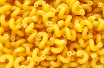 Pile of raw pasta close-up, top view. Italian pasta, texture of pasta cones, top view. Mediterranean cuisine. Wheat pasta, detail of its texture.