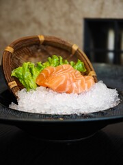 Fresh salmon sashimi artfully presented on a bed of ice with crisp lettuce in a stylish dining setting