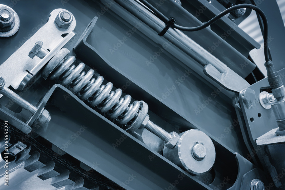 Poster A close up of a machine with a spring inside. The spring is made of metal and is attached to a bolt. The bolt is visible in the middle of the image