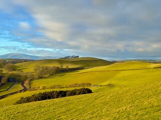 A picturesque landscape of rolling green hills bathed in soft spring sunlight