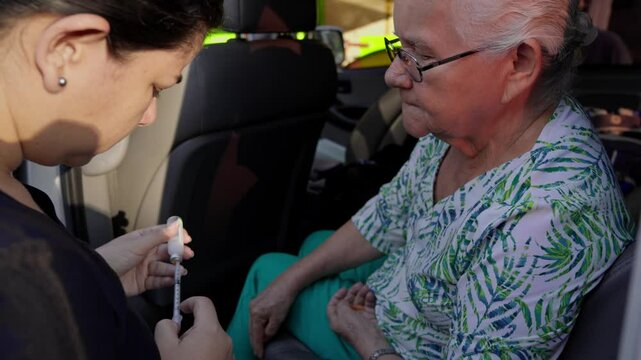 Young woman preparing an insulin injection for her diabetic elderly mother inside a minibus during a trip