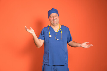 Smiling doctor wearing blue medical uniform and yellow stethoscope showing open hands with orange background, expressing welcome and helpfulness