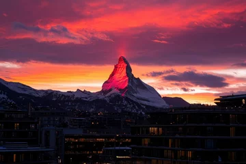 Selbstklebende Fototapeten Matterhorn peak lit up at sunrise over a city. Travel, tourism, winter holiday use © Outkast