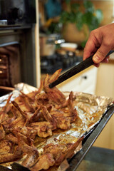 man cooks chicken wings in the oven