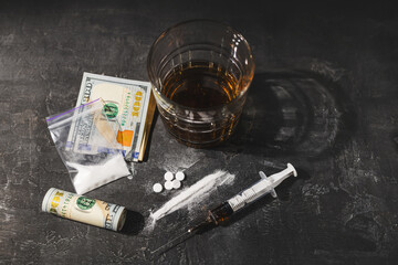 White narcotic pills, an alcoholic drink in a glass, a syringe with a dose of heroin, a line of...